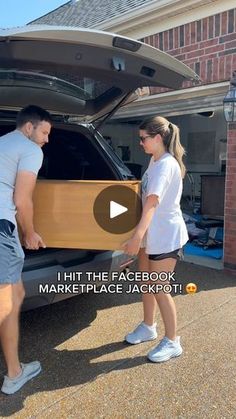 a man and woman unpacking the back of a car with their trunk open