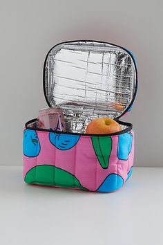 an open lunch box with food inside on a white countertop next to a silver container