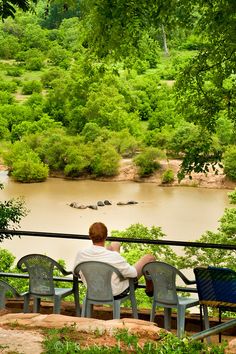 a man sitting on top of a bench next to a river