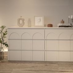 a white cabinet with some vases and plants on top