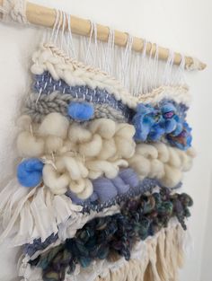 a close up of a wall hanging with different colored yarns and flowers on it