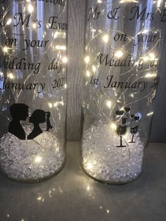 two mason jars decorated with lights and wedding date written on the glass, each jar has an image of a bride and groom