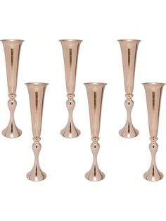 a set of four metal vases sitting next to each other on a white background