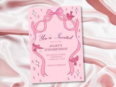 a pink birthday party card with a ribbon and bow on the front, surrounded by satin material