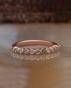 a rose gold wedding band with five diamonds on the top and bottom, sitting on a table