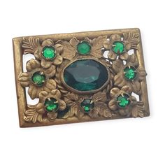 Rectangular brooch of Czechoslovakian origin, made of gold metal with flowers and green rhinestones. It is numbered 187 and signed Made in Czechoslovakia. Modernist era, we date it from approximately 1930. Characteristics: Weight: 16.15 grams. Dimensions: 3.9 cm long and 2.7 cm wide approximately. **Composition Main material: Metal. Contrast: Stamp and numbering. Acid test: Not applicable. Other materials: Green rhinestones. **Additional details: Please look at the photos very carefully, it is n Green Art Nouveau Wedding Brooches, Art Deco Green Brooches For Wedding, Green Art Deco Brooches For Wedding, Antique Green Brooch For Evening, Vintage Green Brooch Jewelry, Vintage Green Brooch For Formal Occasion, Vintage Green Brooch For Evening, Vintage Green Brooches For Formal Occasions, Elegant Green Filigree Brooches