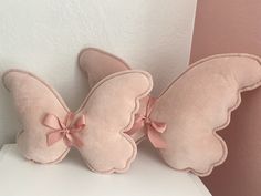 two pink butterfly pillows sitting on top of a white table