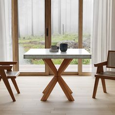 a table with two chairs and a vase on it in front of an open window