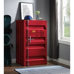 a red cabinet sitting in front of a window next to a rug on the floor