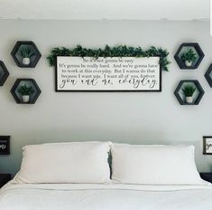 a white bed topped with lots of pillows and framed pictures on the wall above it