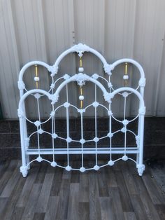 a white iron bed frame with gold knobs on the headboard and foot board