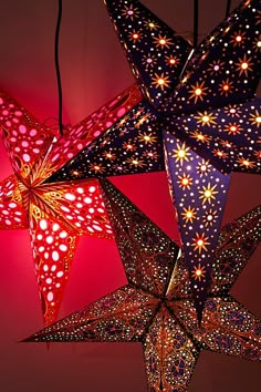 several paper stars are hanging in the air with red lights on them and one is lit up