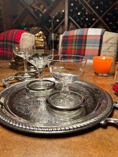 there are three glasses on the silver platter and two candles in front of them