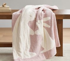 a pink and white blanket sitting on top of a wooden table