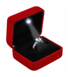 an open red velvet ring box with a diamond ring in it