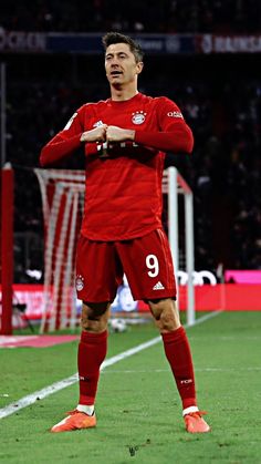 a soccer player is standing on the field with his arms crossed and looking at something