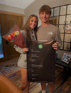 a young man and woman standing next to each other holding up a sign with the names of different foods on it