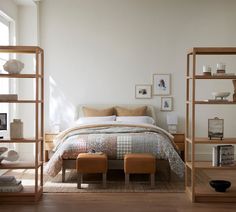 a bed sitting in a bedroom next to a wooden shelf filled with books and pictures