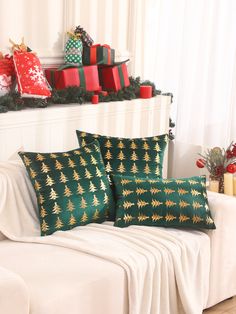 two christmas pillows sitting on top of a white couch next to a pile of presents