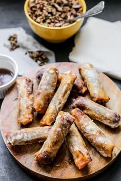 some food is sitting on a wooden plate next to a bowl of sauce and a spoon