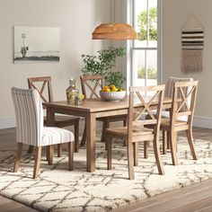 a dining room table and chairs in front of a window with an area rug on the floor