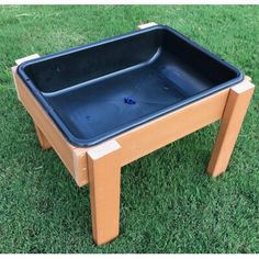 a wooden table with a blue tray on it sitting in the middle of some grass