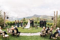 a wedding ceremony in the middle of an outdoor area with mountains in the background and people sitting on lawn chairs