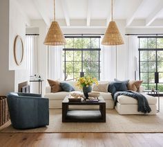 a living room filled with lots of furniture next to large windows and wooden floors in front of them