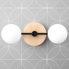 a wall mounted light with two white balls on it's face and one black ball at the top