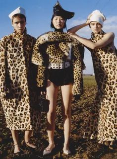 three people dressed in animal print clothing standing next to each other with hats on their heads