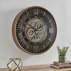 a clock that is on the wall next to a potted plant and some books