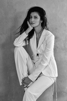 a black and white photo of a woman sitting on a stool with her legs crossed