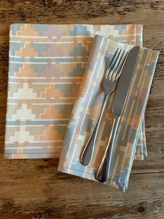 two napkins with silverware on them sitting next to an empty fork and knife