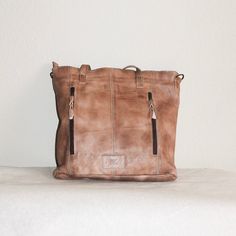 This rustic, leather travel tote is ideal for organizing your belongings on the go. Its brass brads, double exterior pocket, exterior conceal and carry pocket, interior double pocket, interior zipper pocket, and lined interior provide generous space for all your essentials. The perfect blend of functionality and style. About 11” x 14” Shipping on custom items takes 8-10 business days. Rustic Satchel For Travel, Rustic Travel Satchel Bag, Rustic Brown Travel Bag, Leather Backed Tote Shoulder Bag For Travel, Rustic Bags With Leather Handles For Everyday, Rustic Everyday Tote Bag, Vintage Leather Backpack With Zipper For Everyday Use, Rustic Brown Bag For Everyday Use, Rustic Everyday Bags With Leather Lining