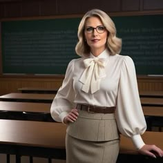 a woman standing in front of desks wearing glasses and a bow tie blouse with long sleeves