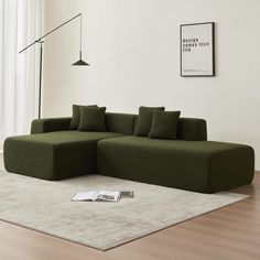 a large green couch sitting on top of a wooden floor next to a white rug