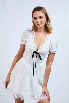 Flaunt your sweet and sassy side in the Te Amo Lace Mini Dress. Made from soft lace and a sheer lined layered fabric, this dress features a flattering neckline adorned with a black velvet bow tie detail. The open back also has a contrast tie that adds a playful touch. Perfect for showing off your unique style! Color: White Mini Length Floral Embroidered Lace Flattering NeckLine With Scalloped Edge Lace Short Puff Sleeve Contrast Front Velvet Tie Bow Open Back With Velvet Tie Bow Scalloped Lace Hemline Lined Fabric 100% Polyester Flirty Lace Mini Dress With Lace Bodice, Flirty Lace Mini Dress With Lace Trim, Feminine Mini Dress With Contrast Lace For Party, Coquette Lace Trim Dress For Date Night, Lace Mini Dress For Date Night, Flirty Lace Dress For Brunch, Coquette Lace Mini Dress With Ruffles, Feminine Mini Dress With Delicate Lace For Brunch, Flirty Lace Dress With Lace Bodice