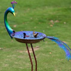 a metal bird bath sitting on top of a green field