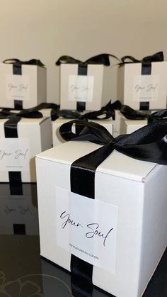 six white boxes with black ribbon and one has a name tag on the front that says, your soul