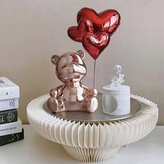 a teddy bear sitting on top of a table next to two heart shaped balloons