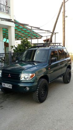 a green suv parked in front of a building