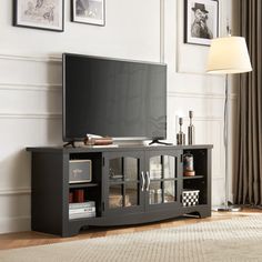 a flat screen tv sitting on top of a wooden entertainment center in a living room