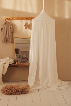 a white canopy bed in a bedroom next to a mirror and rug on the floor