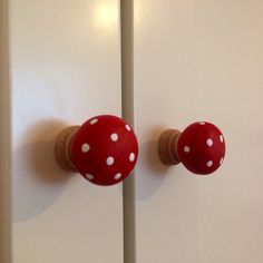 two red and white knobs on the side of a cabinet door with polka dots