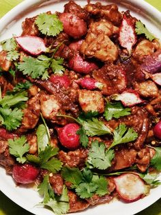 a white plate topped with meat and veggies on top of a green table cloth