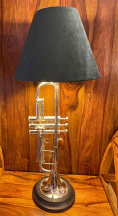 a table lamp with a black shade on it and a wooden wall in the background