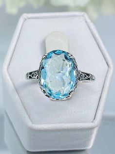 Custom Aqua-Blue Gemstone Ring Made To Order:   Setting Description #70 Here we have an Edwardian reproduction ring in sterling silver filigree with a perfect Simulated/Man-made blue aquamarine gemstone solitaire (or a Natural 6ct to 6.5ct Sky Blue Topaz also available, see last picture in set), all other pictures are the simulated aquamarine option. The full cut oval gem is 14mm in length and 10mm in width. This ring also sits 7mm off the finger. The inside of the band is marked 925 for sterlin Elegant Light Blue Rings For Formal Occasions, Blue Oval Art Deco Rings, Classic Light Blue Jewelry For Formal Occasions, Classic Light Blue Formal Jewelry, Light Blue Classic Jewelry For Formal Occasions, Art Deco Blue Topaz Oval Jewelry, Art Deco Blue Topaz Ring With Accent Stones, Blue Oval Topaz Ring In Art Deco Style, Classic Light Blue Oval Jewelry