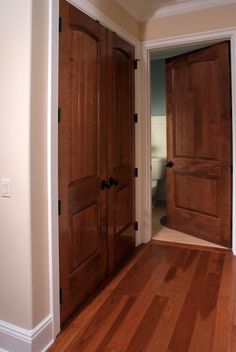 an empty room with two wooden doors and hard wood flooring on the hardwood floors