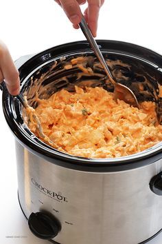 a person is spooning food into a slow cooker