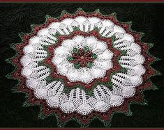 a crocheted doily with red and green trimmings on black background